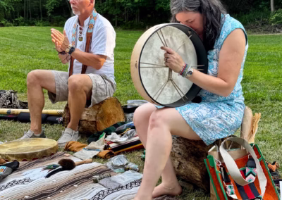 Man and woman playing frame drums outdoors during a Lion's Gate sound healing session