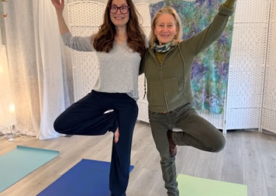 Two women practicing tree pose yoga on mats in the studio
