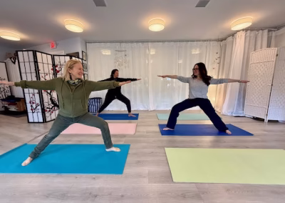 Yoga class practicing warrior II pose in the studio